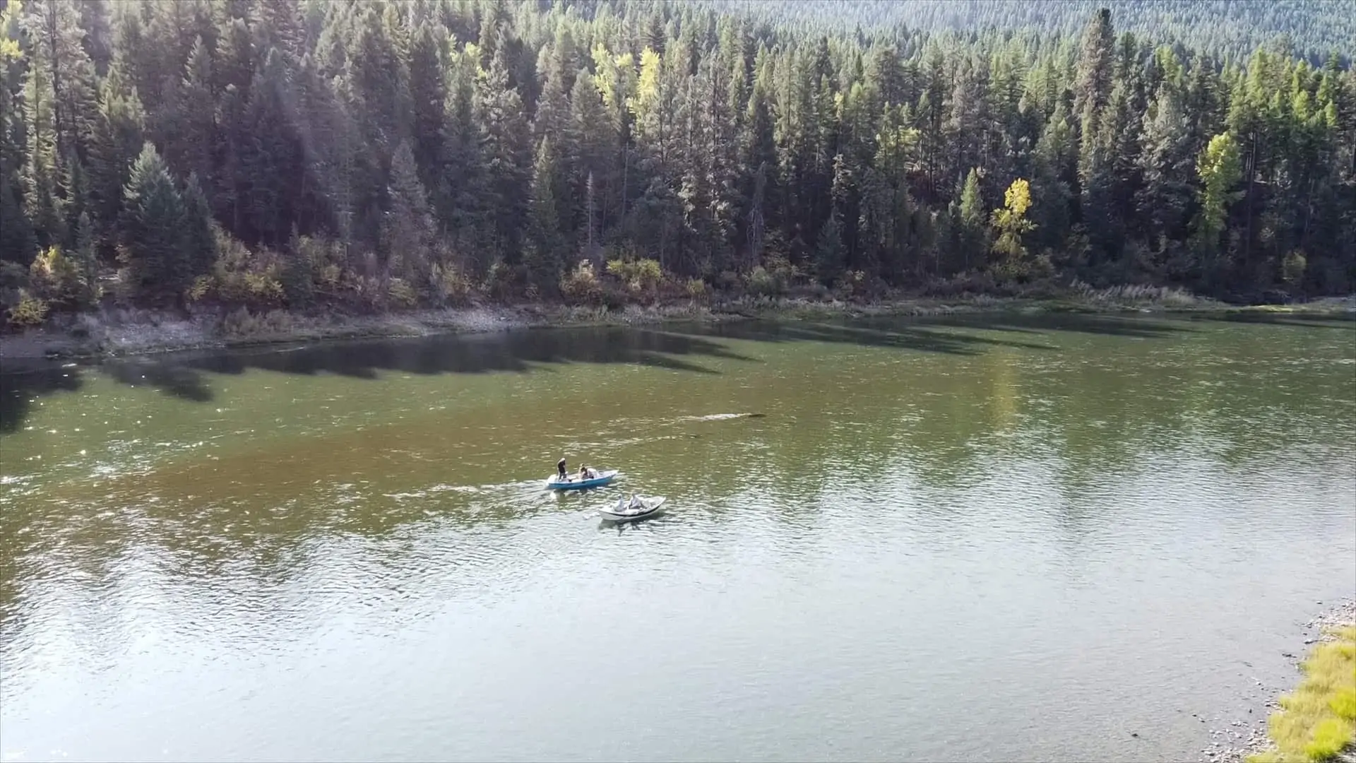 Man reading at table next to Montana river and mountain