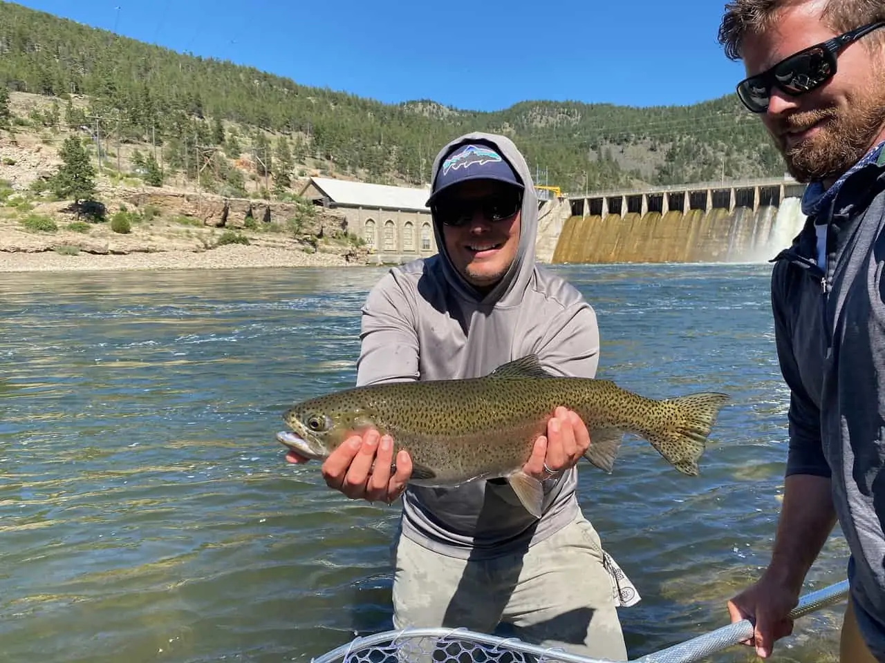 Man holding fish in front of dam